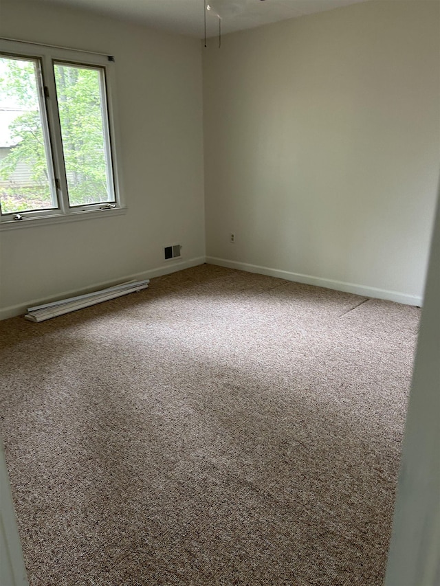 spare room featuring baseboards, carpet, a baseboard heating unit, and visible vents