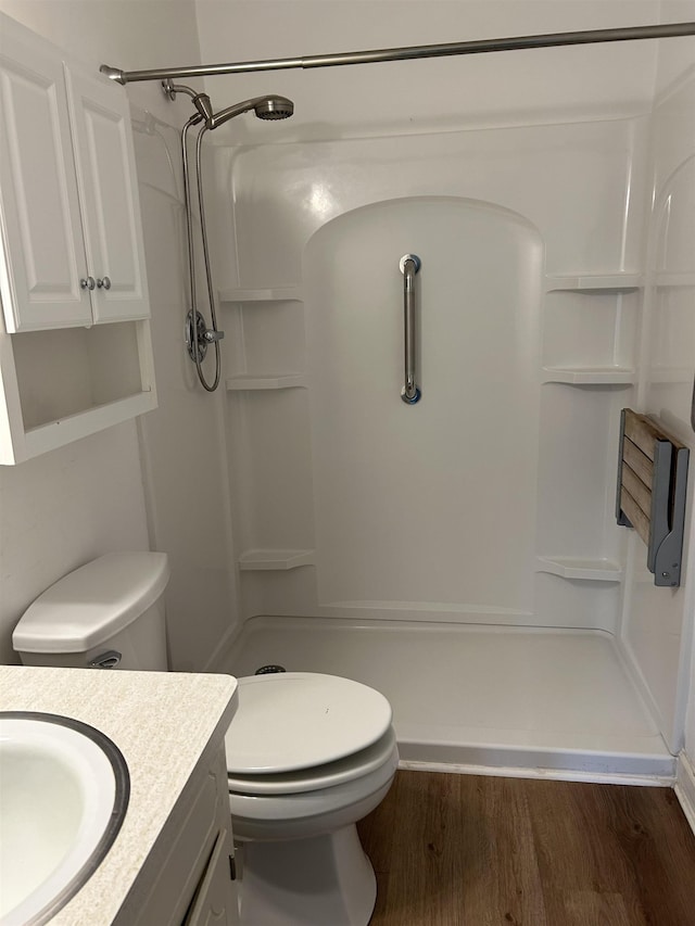 bathroom with vanity, wood finished floors, toilet, and a shower stall