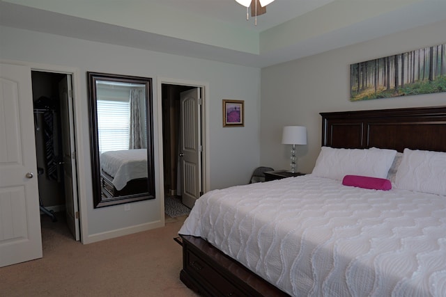 bedroom with baseboards, light carpet, a walk in closet, and a closet