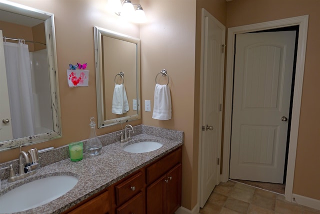 full bathroom with double vanity, baseboards, and a sink