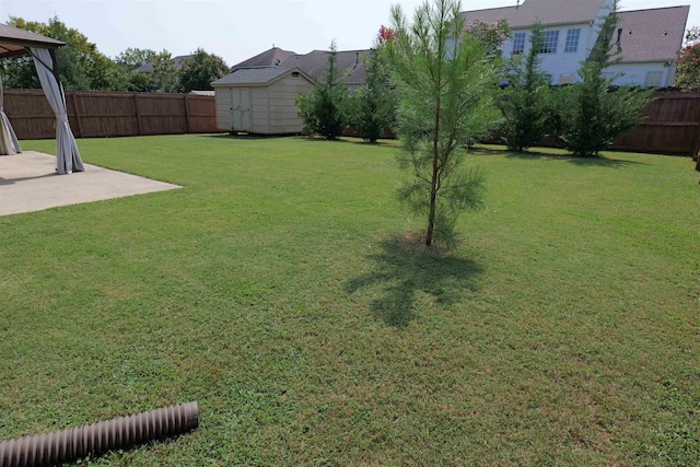view of yard featuring an outdoor structure, a gazebo, a storage shed, a fenced backyard, and a patio