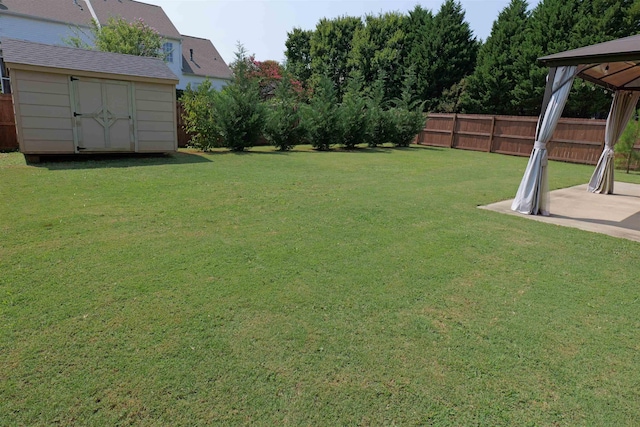 view of yard with a fenced backyard, an outbuilding, a gazebo, and a storage shed