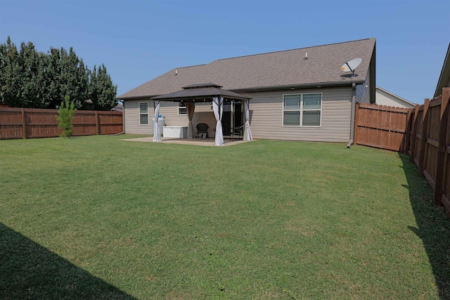 rear view of house with a lawn, a gazebo, a patio area, and a fenced backyard
