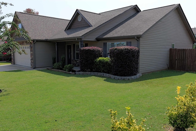 craftsman-style house with fence, roof with shingles, an attached garage, a front yard, and driveway