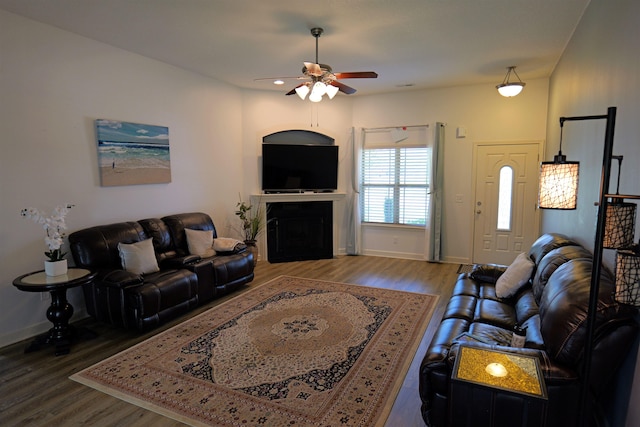 living room with baseboards, ceiling fan, wood finished floors, and a fireplace