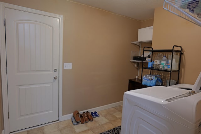 clothes washing area with washer / clothes dryer, laundry area, and baseboards
