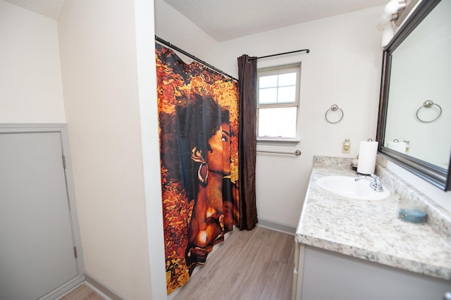 full bath with vanity, a textured ceiling, and wood finished floors