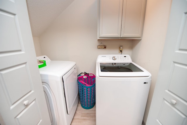 laundry room featuring a textured ceiling, light wood-style flooring, cabinet space, and independent washer and dryer
