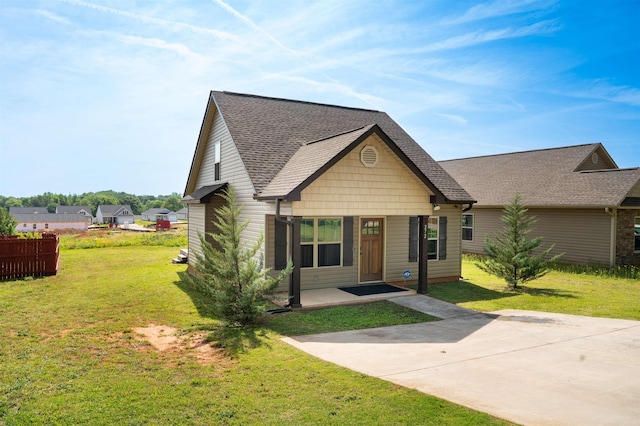view of front of property with a shingled roof, a front lawn, and fence