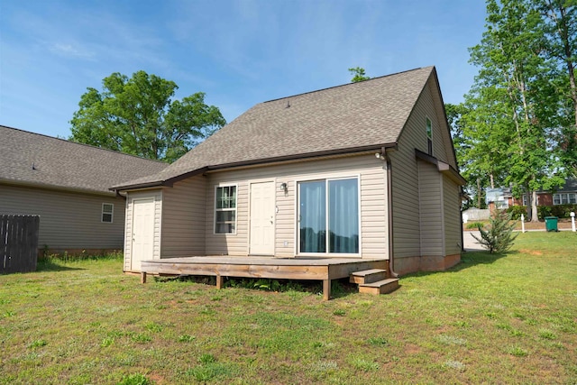 rear view of property featuring a lawn, roof with shingles, and a deck