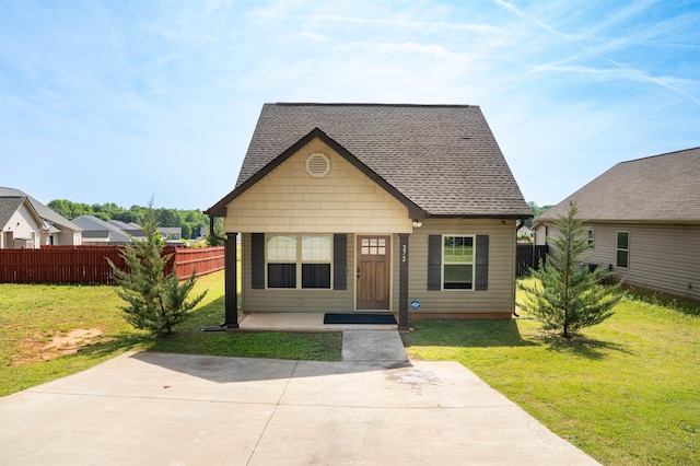 bungalow-style house with fence, roof with shingles, and a front lawn