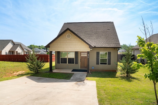 view of front of house featuring fence, roof with shingles, and a front yard
