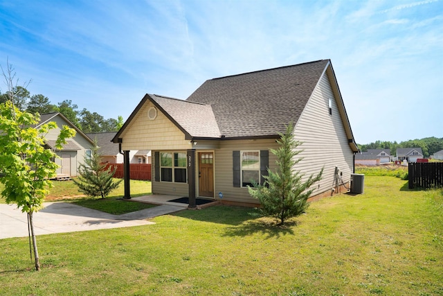 view of front of house featuring fence, cooling unit, and a front lawn