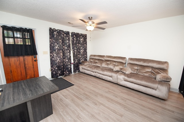 living room with a textured ceiling, ceiling fan, visible vents, and wood finished floors