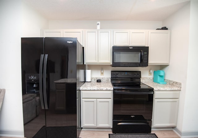 kitchen with light stone counters, light wood finished floors, and black appliances