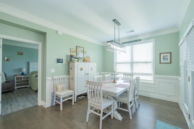 dining area featuring visible vents, dark wood finished floors, crown molding, and wainscoting