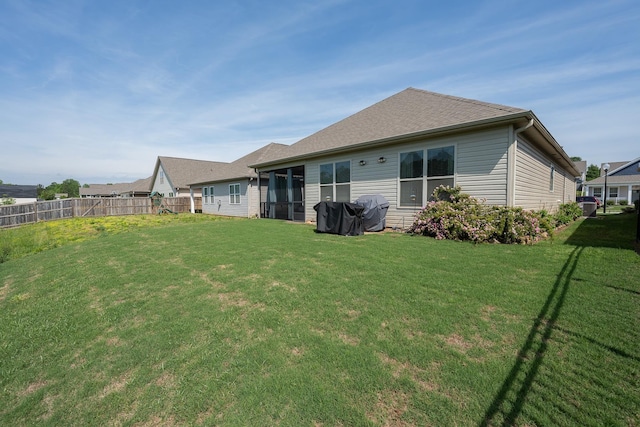 back of house with a fenced backyard and a yard