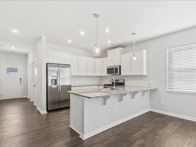 kitchen featuring a sink, appliances with stainless steel finishes, a peninsula, and white cabinetry