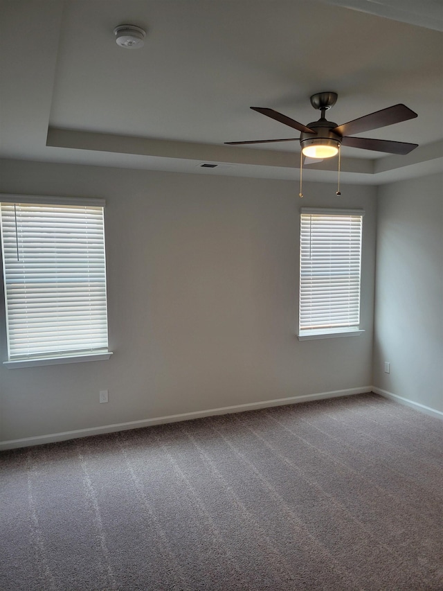 carpeted empty room with baseboards, ceiling fan, and a tray ceiling