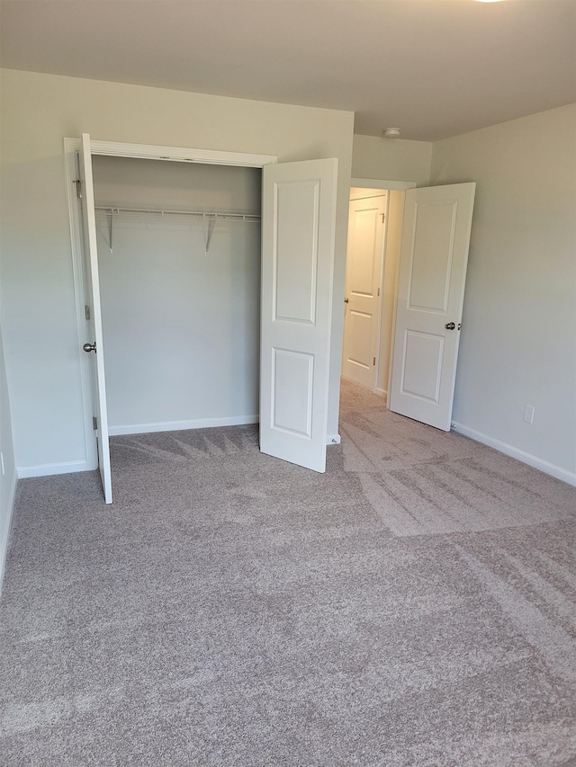 unfurnished bedroom featuring carpet floors, baseboards, and a closet