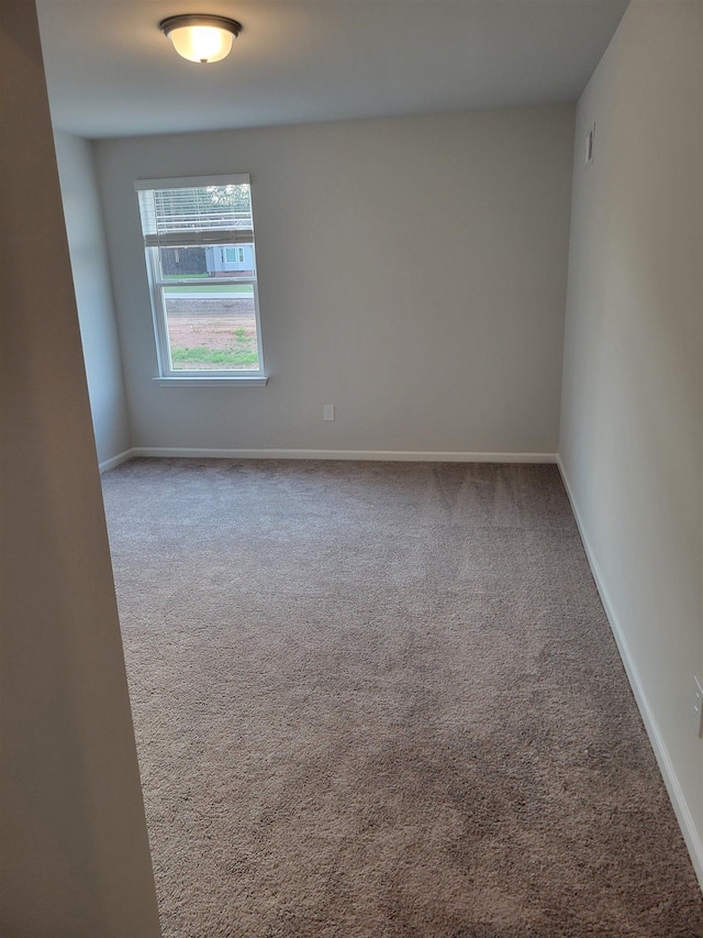 carpeted spare room featuring baseboards