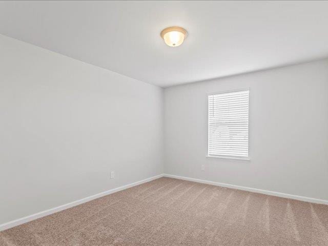 carpeted spare room featuring baseboards