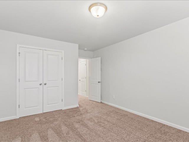 unfurnished bedroom featuring a closet, carpet flooring, and baseboards