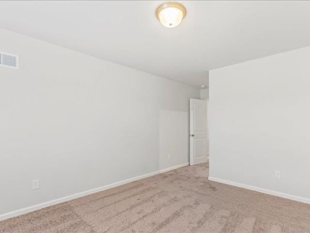 unfurnished room with visible vents, carpet, and baseboards