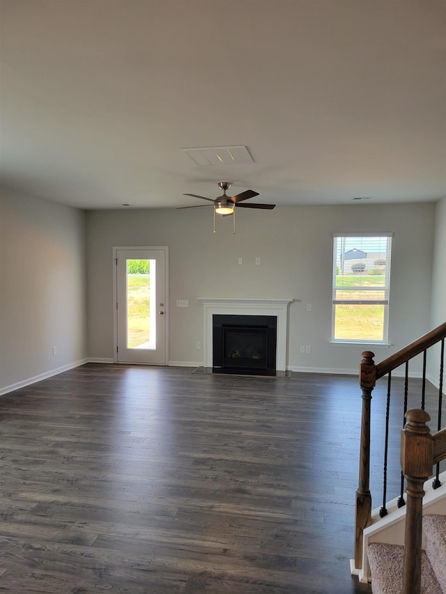 unfurnished living room with baseboards, a fireplace with flush hearth, stairway, and dark wood-type flooring