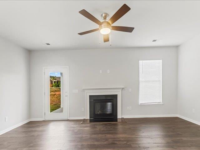 unfurnished living room featuring ceiling fan, baseboards, a fireplace with flush hearth, wood finished floors, and visible vents