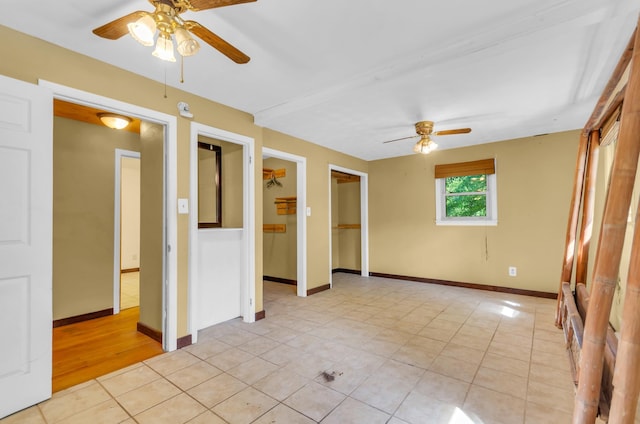 empty room with a ceiling fan, baseboards, and light tile patterned flooring