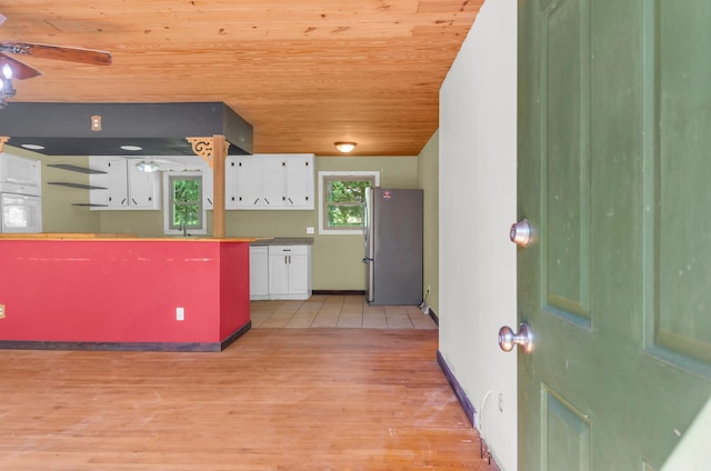 kitchen with white cabinetry, a sink, wooden ceiling, freestanding refrigerator, and light wood-style flooring