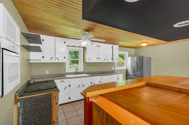 kitchen with white appliances, white cabinetry, a sink, and ventilation hood