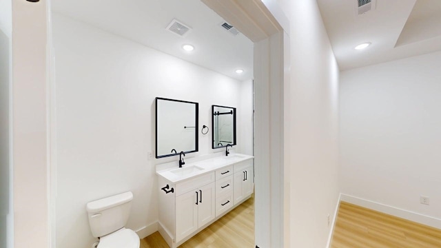 bathroom featuring visible vents, a sink, wood finished floors, and toilet