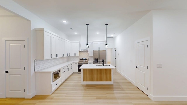 kitchen featuring appliances with stainless steel finishes, a sink, light countertops, tasteful backsplash, and a center island with sink