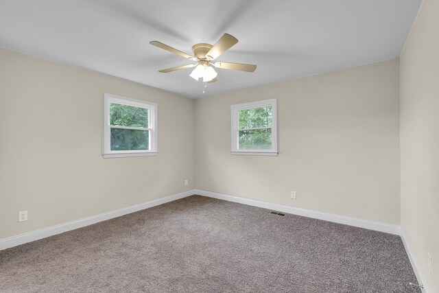 carpeted spare room featuring baseboards, ceiling fan, and a healthy amount of sunlight