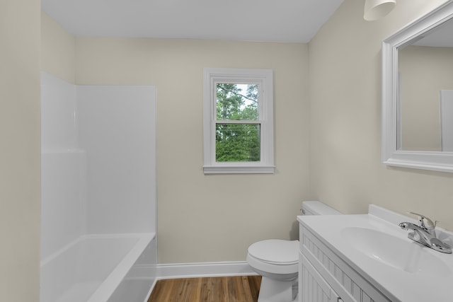 bathroom with shower / bath combination, wood finished floors, baseboards, vanity, and toilet