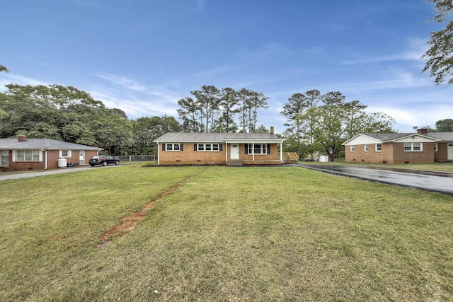 view of front of property featuring crawl space, a chimney, a front yard, brick siding, and aphalt driveway