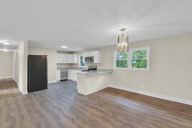 kitchen featuring dark wood-style flooring, stainless steel appliances, baseboards, and a peninsula