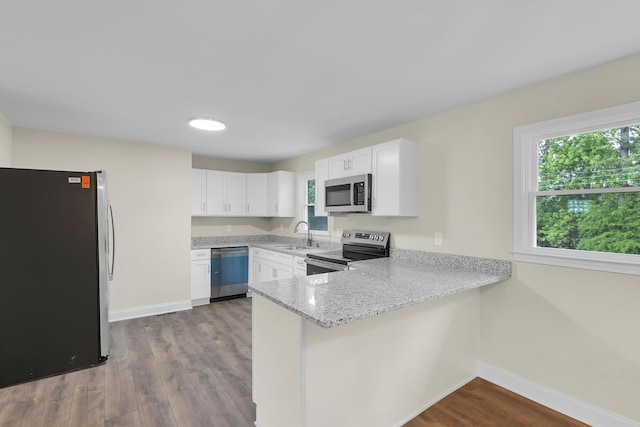 kitchen with appliances with stainless steel finishes, a sink, a peninsula, baseboards, and a wealth of natural light