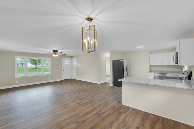 kitchen featuring white cabinets, light stone counters, a sink, stainless steel appliances, and a peninsula