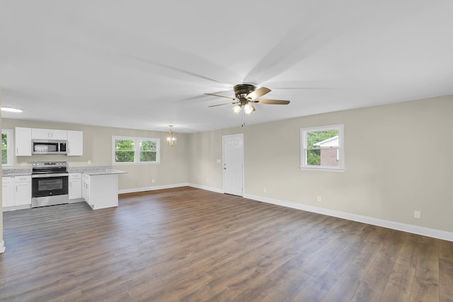 unfurnished living room featuring baseboards, plenty of natural light, ceiling fan, and dark wood-type flooring