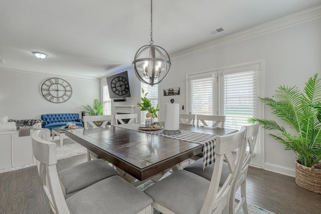 dining area featuring visible vents, crown molding, dark wood-style flooring, an inviting chandelier, and baseboards