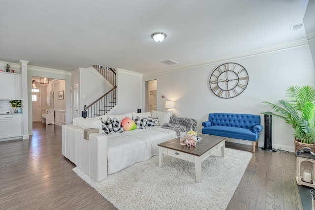 living area with ornamental molding, stairs, wood finished floors, and visible vents