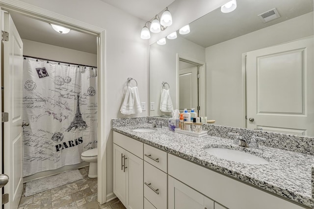 bathroom featuring visible vents, a sink, double vanity, and toilet