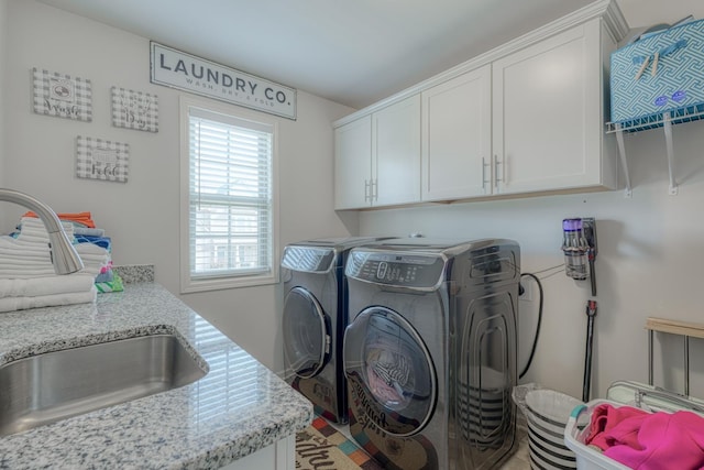 washroom with a sink, cabinet space, and washer and dryer