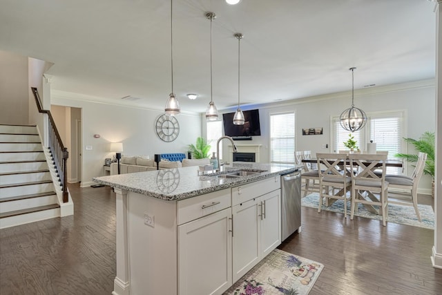 kitchen with light stone counters, a sink, a fireplace, open floor plan, and stainless steel dishwasher