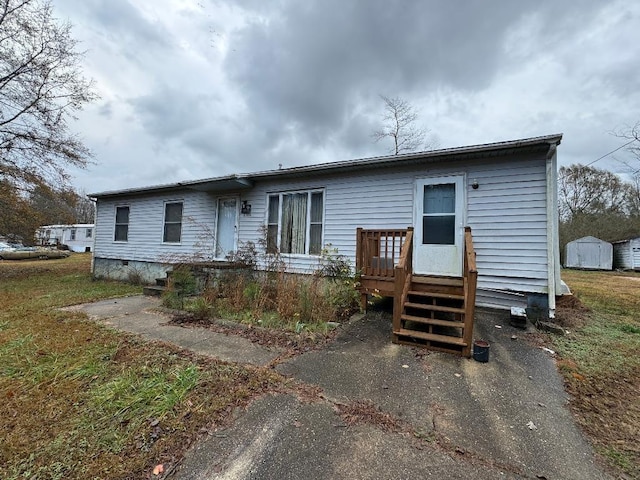 back of house with an outbuilding, a shed, and a wooden deck