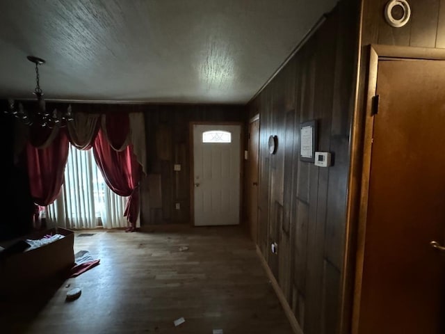 entryway featuring wood walls, wood finished floors, and a notable chandelier