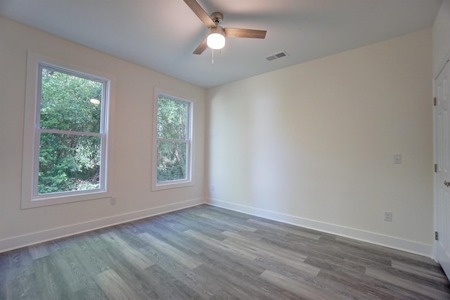 empty room featuring visible vents, a ceiling fan, dark wood-style flooring, and baseboards